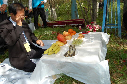9일 오전 러시아 사할린 남단 코르사코프시 제2공동묘지에서 열린 유골 봉환 묘제에서 한 희생자의 유가족이 눈물을 닦고 있다.