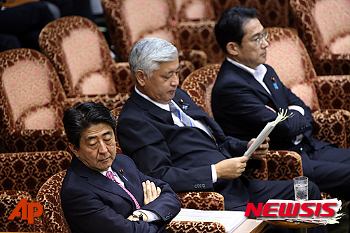 아베 신조(安倍晉三) 일본 총리(왼쪽), 나카다니 겐(中谷元) 방위상(가운데), 그리고 기시다 후미오(岸田 文雄) 외무상(오른쪽)이 17일 오전 도쿄 국회의사당에서 참의원 특별위원회 이사회 개회를 기다리고 있다. 전날 밤 민주당을 비롯한 야당 의원들은 참의원 특위의 안보법안 총괄 질의 개회를 저지하며 국회의사당에서 여당과 밤샘 대치를 벌였다. 같은 날 저녁 국회 밖에서는 수천 명의 일본 시민들의 안보법안 반대 시위가 벌어졌다.