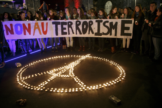 지난 14일 스위스 로잔에서 앞서 하루 전날 밤 프랑스 파리에서 발생한 ‘11·13 파리 테러사건’의 희생자들을 추모하는 집회가 열린 가운데 ‘테러리즘에 반대한다(NON AU TERRORISME)’라고 적힌 팻말을 든 참가자들이 파리 에펠탑 모양으로 밝힌 촛불 주위를 둘러싸고 있다.  AP 연합뉴스