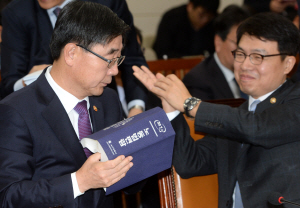16일 국회에서 열린 환경노동위원회 전체회의에서 이기권(왼쪽) 고용노동부 장관이 노동법 편람을 한쪽으로 치우고 있다.