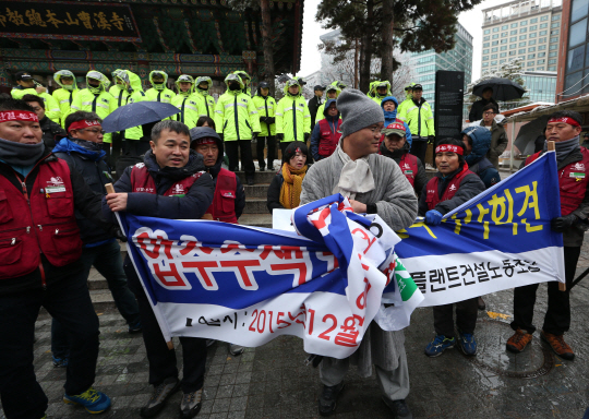 3일 서울 종로구 조계사 입구에서 민주노총 전국플랜트건설노조원들이 경찰의 압수수색을 비판하는 기자회견을 하려 하자 조계사 호법부 관계자가 회견 장소를 옮길 것을 요구하며 노조원들이 펼친 현수막을 걷고 있다.  연합뉴스
