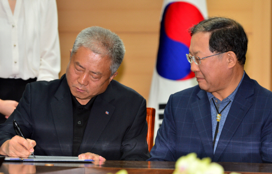 지난해 9월 김동만(왼쪽) 한국노총 위원장이 박병원 한국경영자총협회장이 지켜보는 가운데 노사정 합의문에 서명하고 있다. 뉴시스