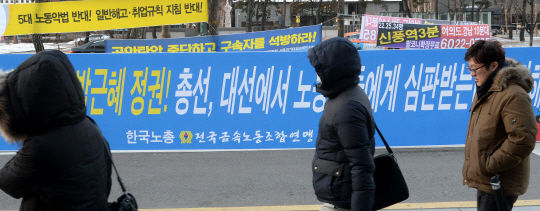 14일 오전 서울 여의동 국회 앞 도로에서 시민들이 박근혜정부의 노동정책을 비판하는 한국노총의 현수막 사이로 지나가고 있다.