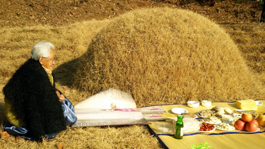 지난 2014년 12월 12일 조병만 할아버지의 첫 기일에 강계열 할머니가 집 뒷산 할아버지 무덤에서 제사를 지내며 영화 ‘님아, 그 강을 건너지 마오’ 포스터를 영전에 올리고 있다. 촬영 도중 별세한 할아버지는 이 영화의 흥행 성공을 보지 못했다.