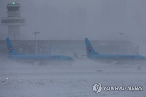 최강 한파로 제주공항에서 항공기 운항이 잠정 중단된 24일 오전 강한 눈발에 가려 항공기들이 희미하게 보이고 있다