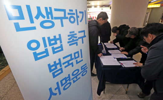 26일 강원 춘천시 중앙로 지하상가에서 시민들이 ‘민생 구하기 입법 촉구 1000만 서명운동’에 참여해 서명을 하고 있다. 연합뉴스