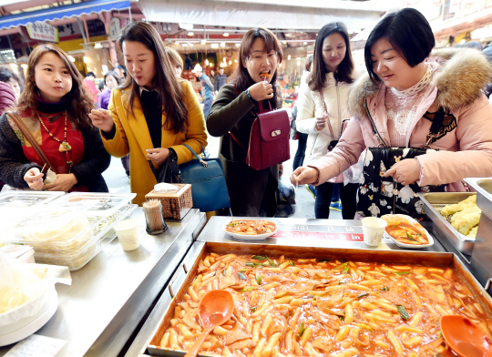 회사 포상휴가차 인천을 찾은 3000여 명의 중국 아오란그룹 관광객 중 일부가 27일 인천 남동구 모래내시장에서 떡볶이 등 간식을 사 먹으며 즐거워하고 있다.   뉴시스