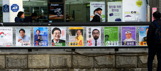 4·13 국회의원 총선거 공식 선거운동이 시작된 31일 오전 서울 종로 선거구에 속한 경복궁 대로변에서 한 시민이 담벼락에 붙어 있는 후보자들의 벽보를 살펴보고 있다. 곽성호 기자 tray92@