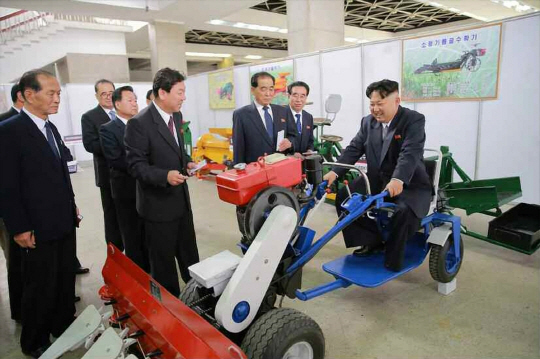 지난 9일 제7차 노동당대회 폐막 이후 첫 공개 행보에 나선 김정은(오른쪽) 북한 노동당 위원장이 파종기에 직접 탑승해 운전하는 모습을 연출하고 있다. 노동신문은 13일 김 위원장의 기계설비 전시장 시찰소식을 보도했다.  연합뉴스