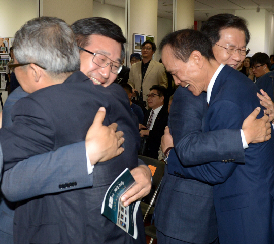 5·18민주화운동 36주년을 기념해 16일 서울시청 지하 시민청 갤러리에서 ‘기억의 회복’이란 제하에서 열린 광주 치유 사진전에서 천정배(오른쪽) 국민의당 공동대표와 윤호중(왼쪽) 더불어민주당 의원이 5·18 유공자와 포옹을 하고 있다. 뉴시스