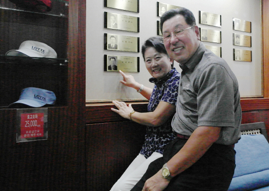 김상윤(오른쪽) 챔프와 나란히 앉은 아내 목애희 씨가 지난달 30일 롯데스카이힐 제주 골프장 클럽하우스 내 챔피언 라운지 벽면에 부착된 남편의 ‘챔피언 명패’를 가리키고 있다.
