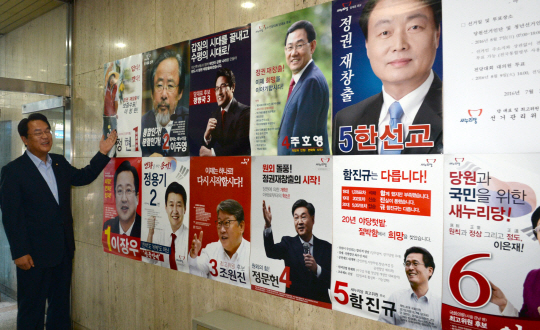 정진석 새누리당 원내대표가 1일 오전 여의도 당사 현관에 붙은 당 대표 및 최고위원 후보들의 포스터를 보며 웃고 있다.