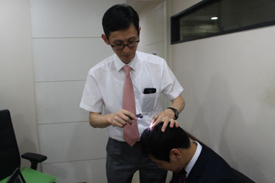 김종혁 예담피부과 원장이 한 남성의 탈모상태를 점검하고 있다.