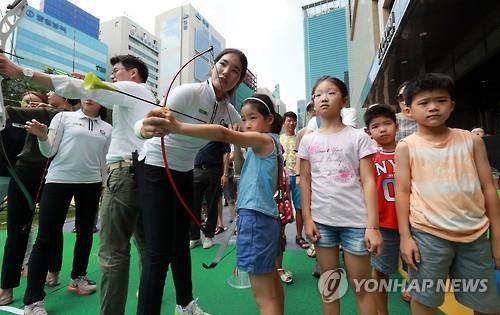현대백화점 양궁단 선수들이 시민들의 양궁체험을 돕는 모습 [연합뉴스 자료사진]