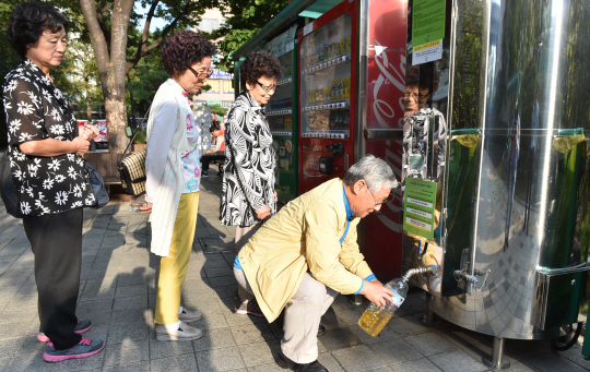 노원구 주민들이 지난 23일 서울 노원구 상계동 노원구청 광장에 설치된 유용미생물(EM) 발효액 보급기에서 발효액을 페트병에 담고 있다.
