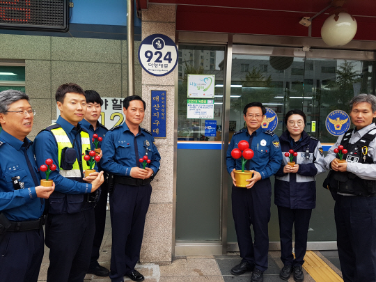 윤수원(오른쪽 세 번째) 수원 서부경찰서 매산지구대장과 대원들이 21일 지구대 정문 앞에서 사랑의 열매 나무 조형물을 들고 지속적인 기부를 약속하고 있다.