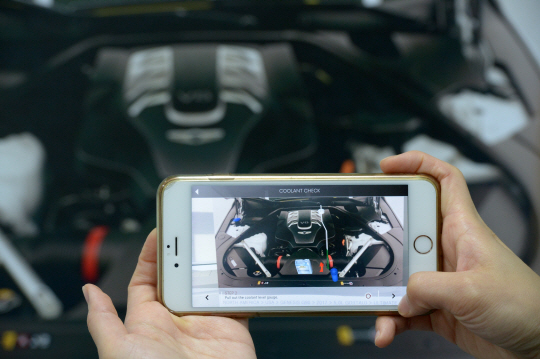 서울 서초구 강남대로 증강현실(AR) 기술 회사인 맥스트 사무실에서 한 직원이 스마트폰으로 AR 매뉴얼을 시연하고 있다. 냉각수를 점검하는 방법이 AR로 구현된 붉은 화살표로 안내되고 있다.