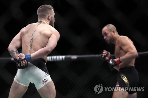 맥그리거(왼쪽)가 알바레스와 경기 도중 양손을 뒤로 숨기며 도발하고 있다. [AP=연합뉴스]