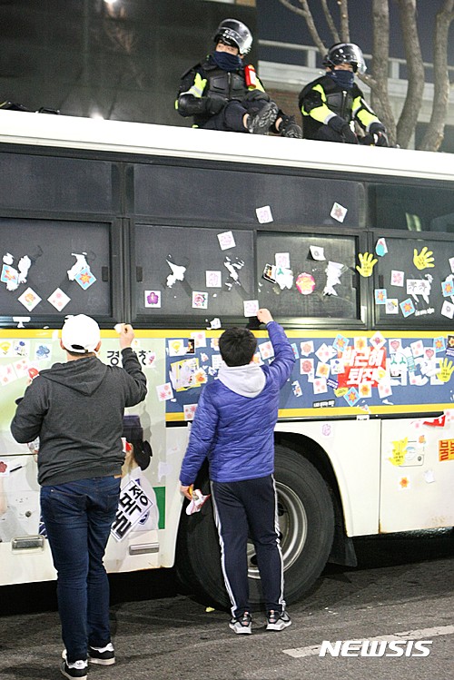 일 오후 서울 종로구 광화문광장 일대에서 열린 제6차 민중총궐기에 참가한 시민들이 경찰 차벽에 붙은 스티커를 때고 있다.