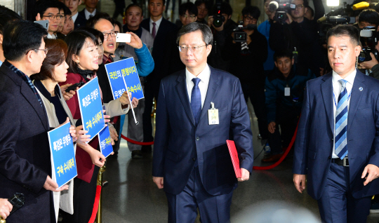 우병우(가운데) 전 청와대 민정수석이 22일 오전 최순실 국정농단 사건 국회 국정조사 특별위원회 청문회장 앞에서 더불어민주당 의원들이 “우병우 구속수사”를 요구하는 팻말을 들고 구호를 외치는 가운데 그 앞을 지나가고 있다.