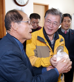 문재인(오른쪽) 전 더불어민주당 대표가 1일 광주 서구 서창동 발산경로당을 찾아 주민들로부터 계란 선물을 받고 있다.