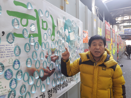 지난해 말 대구 중구 서문시장 4지구 대형화재로 피해를 입은 상인 손성봉 씨가 1일 현장 가림막에 시민들이 남긴 ‘희망 메시지’를 가리키며 “반드시 재기하겠다”고 다짐하고 있다.