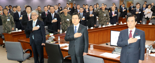 황교안(가운데) 대통령 권한대행 국무총리가 4일 오전 정부서울청사에서 열린 외교 안보 부처 업무보고에 참석해 한민구(오른쪽) 국방부 장관, 윤덕민(왼쪽) 국립외교원장과 함께 국기에 대한 경례를 하고 있다.
