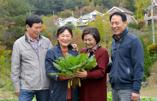 전중호·김복윤 부부(왼쪽)와 용경순·문영균 씨 부부가 명동리 마을 자신들의 전원주택 앞에서 수확한 배추를 들고 이야기를 나누고 있다.