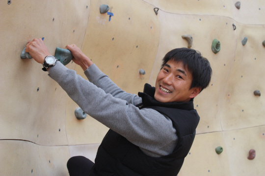 지난 22일 경남 진주종합경기장 암벽장에서 인공암벽을 오르며 밝게 웃고 있는 최강식 씨. 최 씨는 손가락을 잃어 생활이 불편하지 않으냐고 묻자 거리낌 없이 양손을 탁자(왼쪽 사진)에 올려 보이며 “장애라고 생각하지 않는다”고 하면서 사진 촬영에도 흔쾌히 응했다.
