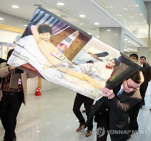 (서울=연합뉴스) 한 보수단체 회원이 24일 오후 서울 여의도 국회 의원회관 로비에서 더불어민주당 표창원 의원 주최로 열린 ‘곧, 바이! 展’ 시국비판 풍자 전시회에서 박근혜 대통령을 나체 상태로 풍자한 그림을 집어 던지고 있다.