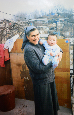 노수녀의 젊은 시절, 도시 빈민가에서 아이를 보듬어 주고 있는 모습.