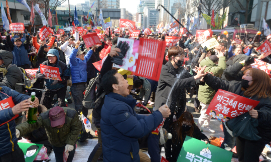 박근혜 대통령에 대한 헌법재판소의 탄핵 인용 소식이 전해지자 10일 오전 서울 종로구 안국동 거리에서 열린 탄핵 찬성 집회에 참석한 시민들이 환호하며 샴페인을 터뜨리고 있다.