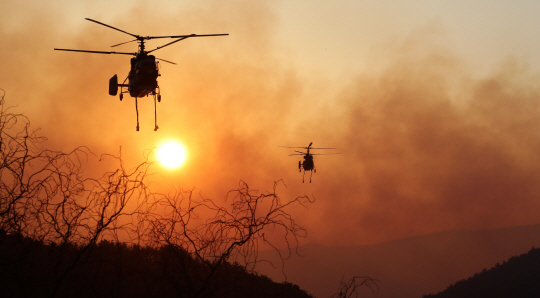 강원 강릉시 옥계면의 한 야산에서 발생한 산불이 이틀째 이어지고 있는 가운데 10일 오전 산림청 헬기가 자욱한 연기를 뚫고 진화 작업에 나서고 있다. 연합뉴스