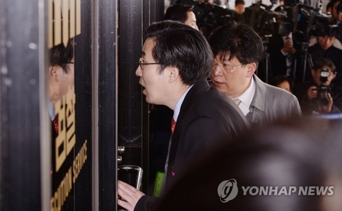 (서울 사진공동취재단=연합뉴스) 뇌물수수 등 13개 범죄혐의로 검찰에 소환된 박근혜 전 대통령 측 손범규 변호사가 21일 오전 서울중앙지검 현관 출입문에서 안쪽에 대고 이야기를 하고 있다.