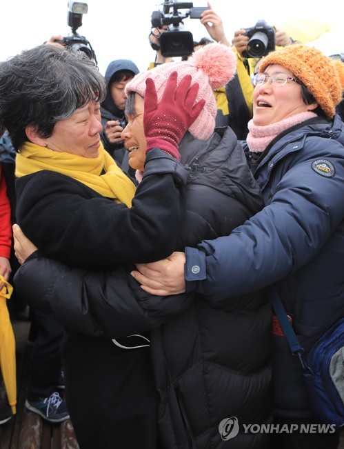 세월호 미수습자 가족들이 25일 오후 사고해역에서 인양과정을 지켜보고 전남 진도군 팽목항으로 돌아온 뒤 자원봉사자와 눈물을 흘리고 있다.