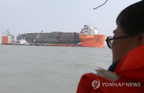(진도=연합뉴스) 세월호 미수습자 가족들이 27일 오전 전남 진도군 세월호 사고 해역 인근에서 반잠수선에 실려 마지막 항해를 위해 해수 배출 등 준비작업 중인 세월호를 바라보고 있다. 세월호는 배수와 방제 작업을 마치고 30일 전후 목포신항으로 출발한다.