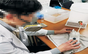 경찰에 적발된 중국산 액상 니코틴 수입업체의 직원이 3일 부산 해운대구 오피스텔에서 불법으로 전자담배 원료를 제조하는 장면을 재연하고 있다.