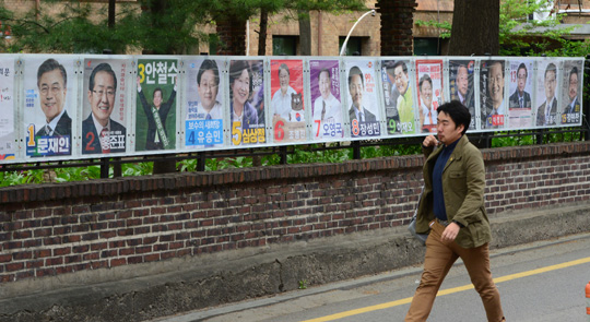 제19대 대통령선거 후보 포스터 부착이 시작된 20일 오전 서울 종로구 동숭동 거리에서 한 시민이 후보 포스터를 보며 걸어가고 있다. 역대 최다인 15명이 출마하면서 벽보 길이도 역대 최장인 10.14m에 달한다.