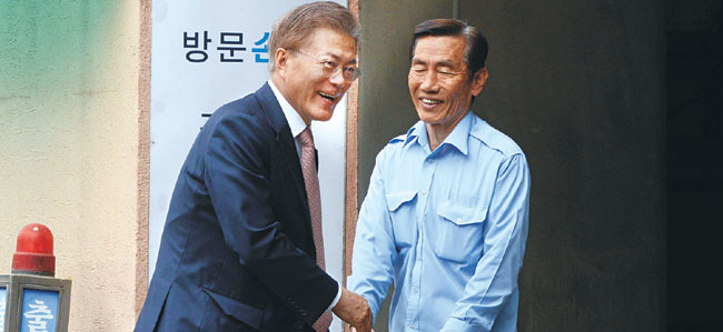 문재인 대통령이 11일 오전 청와대 출근을 위해 서울 서대문구 홍은동 자택을 나서다 경비원과 악수를 하고 있다.