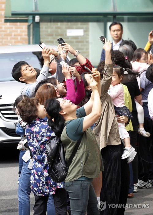 (서울=연합뉴스) 13일 오전 서울 서대문구 문재인 대통령 홍은동 사저 앞에서 주민들이 창문으로 인사하는 김정숙 여사를 휴대폰으로 촬영하고 있다.