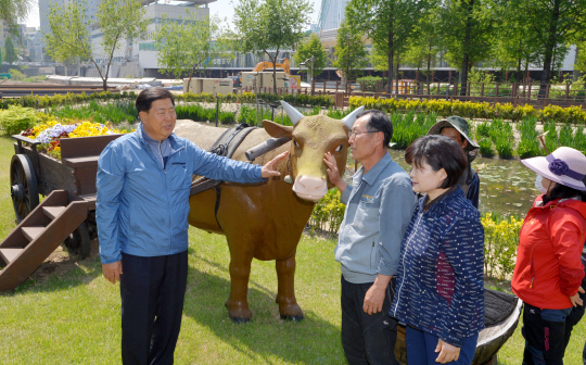 조길형(왼쪽) 영등포구청장이 13일 양평유수지생태공원에 서 있는 모형 소를 쓰다듬으며 주민들과 얘기를 나누고 있다.