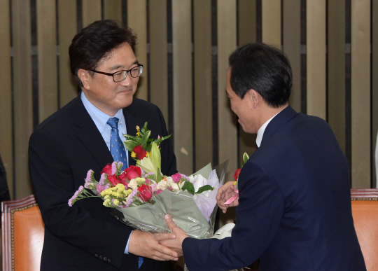 16일 오전 더불어민주당 신임 원내대표로 선출된 우원식(왼쪽) 의원이 우상호 전 원내대표로부터 축하 꽃다발을 받고 있다.