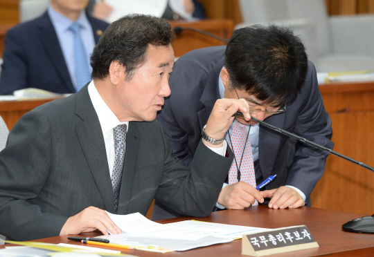 이낙연(왼쪽) 국무총리 후보자가 자신에 대한 국회 인사청문회 이틀째인 25일 오전 청문회장에서 손으로 마이크를 가린 채 총리실 관계자와 귀엣말을 나누고 있다.