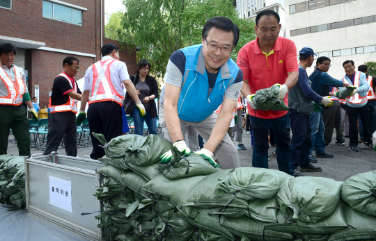성장현(맨 앞) 서울 용산구청장이 지난 5월 30일 용산구 원효빗물펌프장에서 실시된 ‘풍수해 대비 수방 종합훈련’에 참가해 주민들과 함께 저지대 침수방지를 위한 모래 마대 쌓기 작업을 하고 있다.