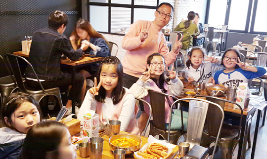 이정범 동천초등학교 교사가 지난 4월 반 아이들과 함께 음식점에서 즐거운 시간을 보내며 손가락으로 ‘V’를 지어 보이고 있다.  이정범 교사 제공