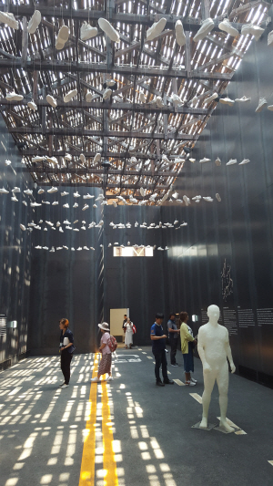 지난달말 광주 동구 옛 전남경찰청 민원실에 조성된 5·18민주평화기념관 제2관의 전시물을 관람객들이 보고 있다. 천장에는 주인 잃은 운동화들이 매달려 있고 실내 스피커에서는  윤이상 선생의 ‘광주여 영원하라’가 울려퍼지고 있다.