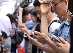 출근 시간에 직장인들이 스마트폰으로 음악이나 동영상을 감상하고 있다. 국내 이동전화 가입자가 6200만 명을 넘어선 가운데 스마트폰이 생활필수품으로 자리 잡은 모습이다.  연합뉴스