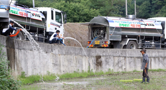 21일 남양유업 임직원들이 우유 수송 차량에 물을 싣고 와 계속된 가뭄으로 물이 없어 모내기를 못 한 세종시 전의면 김영기 씨 논에 물을 공급해 주고 있다.  연합뉴스