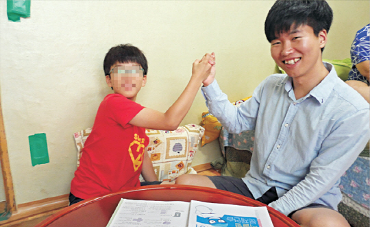 황대철 씨가 상민이 동생 용진이와 공부하면서 두 손을 맞잡고 파이팅을 외치고 있다.  초록우산어린이재단 제공