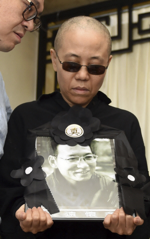 19일 중국 당국에 의해 ‘강제 여행’을 하고 있는 노벨평화상 수상자이자 인권운동가인 고 류샤오보의 아내 류샤가 지난 15일 선양시에서 남편의 영정을 들고 있다.